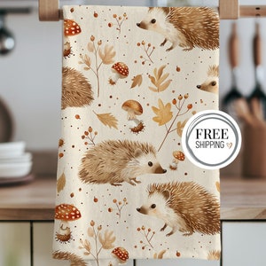 May include: A beige kitchen towel with a repeating pattern of hedgehogs, mushrooms, and autumn leaves. The text "FREE SHIPPING" is in a circle on the towel.