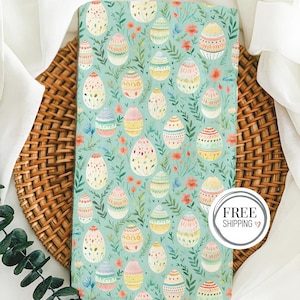 May include: A teal blue fabric with a repeating pattern of colorful Easter eggs. The eggs are decorated with various designs and colors, including pink, yellow, green, and blue. The fabric is perfect for crafting projects, such as making Easter decorations or sewing a festive tablecloth.