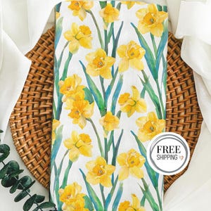 May include: A white tea towel with a watercolor pattern of yellow daffodils and green leaves. The text "FREE SHIPPING" is printed on a gray circle in the bottom right corner.