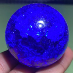Peut inclure: Une bille de verre bleu foncé avec un motif tourbillonnant et texturé. La bille est ronde et lisse.