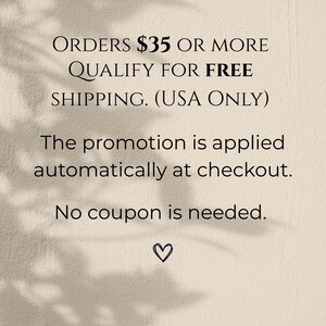 May include: Text on a beige background states "ORDERS &pound;35 OR MORE QUALIFY FOR FREE SHIPPING. (USA ONLY)". Further text explains the promotion is applied automatically at checkout, and no coupon is needed. A small heart is at the bottom.