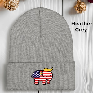 May include: A heather grey beanie hat with an embroidered elephant design. The elephant's body is the American flag, and it has a yellow hairstyle. The text "Heather Grey" is printed on the right side. A political statement.