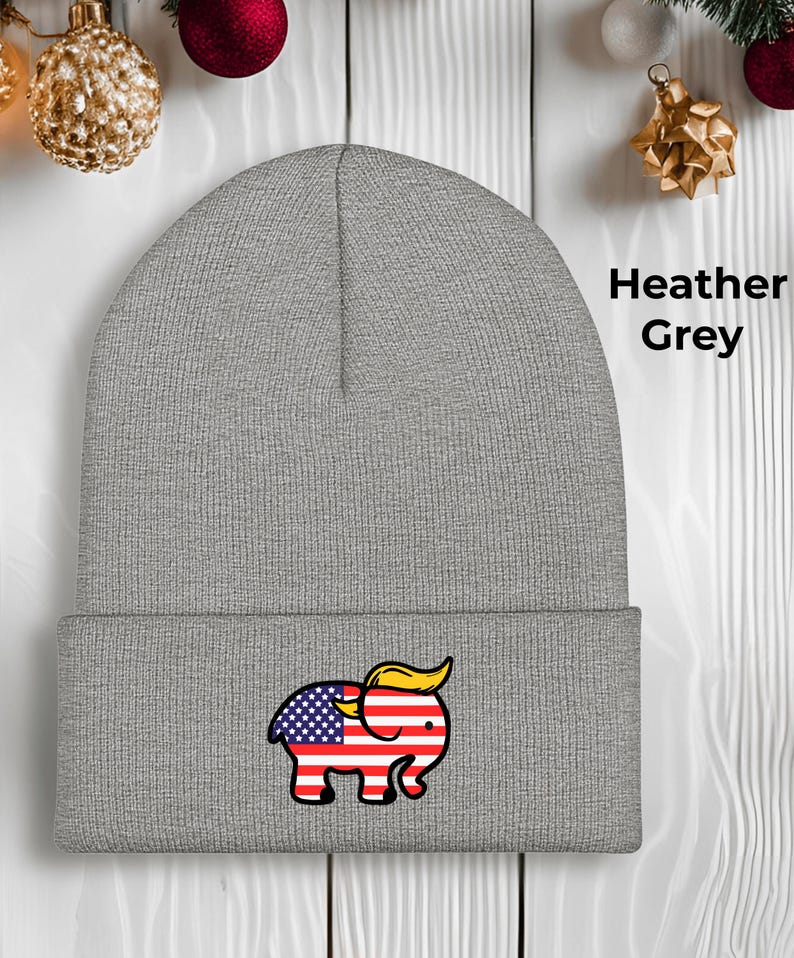 May include: A heather grey beanie hat with an embroidered elephant design. The elephant's body is the American flag, and it has a yellow hairstyle. The text "Heather Grey" is printed on the right side. A political statement.