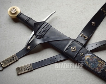 May include: A medieval-style sword with a black leather sheath and belt. The sword features a silver blade, a black handle, and a decorative pommel. The sheath is adorned with gold-colored accents and an illustration.