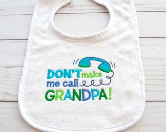 May include: White baby bib with green, blue, and white embroidery that says "DON'T make me call GRANDPA!" with a blue phone graphic.