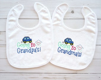 May include: Two white baby bibs with embroidered blue cars and the text "Going to Grandpa's!" and "Going to Grandma's!"
