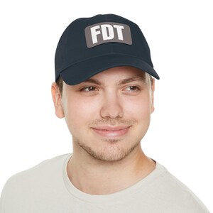 May include: A navy blue baseball cap with a gray patch that says "FDT" in white letters.