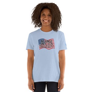 Puede incluir: Una camiseta azul claro con el texto "NO KINGS SINCE 1776" en un dise&ntilde;o patri&oacute;tico. El dise&ntilde;o incluye la bandera estadounidense y la frase "SERIOUSLY WE FOUGHT A WHOLE WAR ABOUT IT".