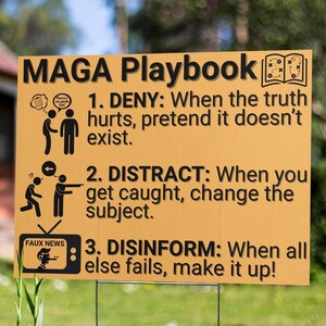 May include: A yellow sign with black text and illustrations, titled "MAGA Playbook." The sign outlines three steps: Deny, Distract, and Disinform. The sign is displayed outdoors, with a green background of grass and foliage.