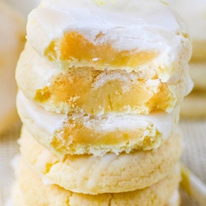May include: A stack of four lemon cookies with a white icing on top. The cookies are slightly yellow in color and have a soft, crumbly texture.