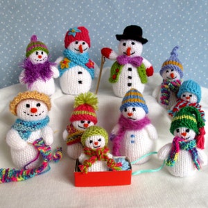 Könnte beinhalten: Eine Gruppe von zehn gestrickten Schneemann-Ornamenten, jedes mit einzigartigen Hüten, Schals und Accessoires. Die Schneemänner sind aus weißem Garn gefertigt und haben schwarze Augen und Knöpfe. Einige Schneemänner halten Wollknäuel oder Schlitten.