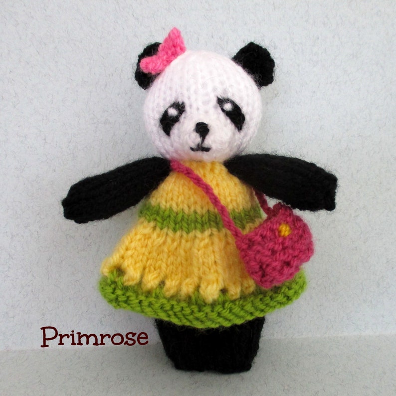 May include: A knitted panda doll wearing a yellow and green striped dress with a pink purse. The doll has a pink bow on its head and black eyes.