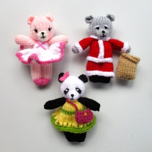 May include: Three knitted stuffed animals: a pink ballerina bear, a gray bear wearing a red Santa suit, and a black and white panda bear wearing a yellow and green dress.