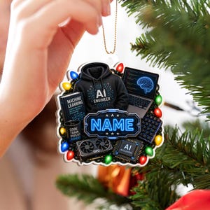 May include: A decorative ornament featuring a black hoodie with AI ENGINEER text, a laptop displaying a brain graphic, a book titled MACHINE LEARNING, a mug with CODE TRAIN DEPLOY REPEAT, a GPU, an AI accelerator, and a central plaque with NAME.