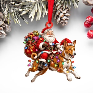 May include: A flat Christmas ornament featuring Santa Claus riding a brown and white dog. Santa wears a red suit and carries a sack of colorful gifts. The dog wears a red Santa hat and is wrapped in multicolored string lights. Text reads Name and Asher.