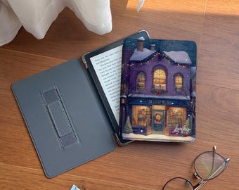 Pode incluir: Uma capa de e-reader cinza aberta com um suporte, uma capa decorativa com uma cena de livraria de inverno, um tubo de loção azul e óculos redondos com armação dourada estão em uma superfície de madeira.