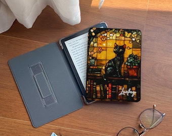 Könnte beinhalten: Ein schwarzer E-Reader mit einer bunten Glasmalerei-Hülle, die eine Katze und das Wort "Lucky" zeigt.