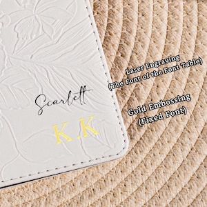 May include: Close-up of a white leather item with embossed floral design. The name "Scarlett" is written in black script, with gold embossed initials "K.K." below. Text on the right indicates "Laser Engraving" and "Gold Embossing."