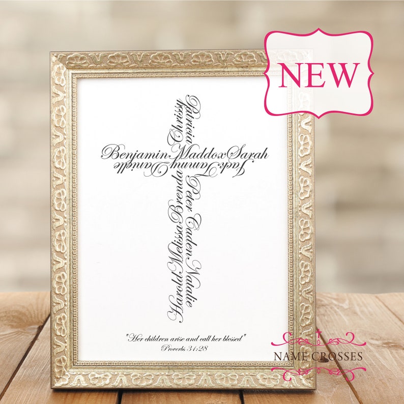 May include: A framed print with a gold-colored ornate frame. The print features a cross made of names in black script. The text "Her children arise and call her blessed" is at the bottom, with "Proverbs 31:28" below it. A pink "NEW" tag is in the upper right corner.