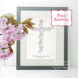 May include: Framed artwork featuring a cross shape composed of names in elegant script. The artwork is in a gray frame, with a pink flower arrangement on the left. The words "Free Shipping" are in a pink bubble on the right. The text "Name Crosses" is at the bottom.