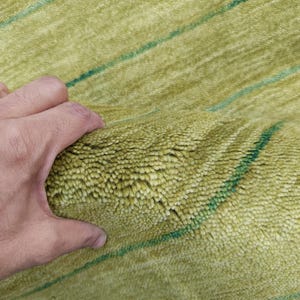 May include: A thick, high-pile rug featuring a vibrant lime green color with thin, horizontal dark green stripes running across the textured surface. The material appears soft and dense, showcasing a deep, plush construction throughout.
