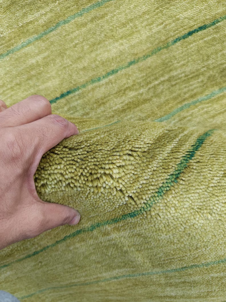 May include: A thick, high-pile rug featuring a vibrant lime green color with thin, horizontal dark green stripes running across the textured surface. The material appears soft and dense, showcasing a deep, plush construction throughout.
