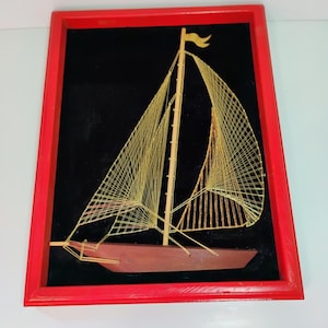 Obra de arte con hilos de velero vintage de los años 70, hilo dorado tensado entre clavos sobre terciopelo negro en un marco de madera.