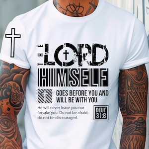 Könnte beinhalten: Ein weißes T-Shirt mit einem schwarzen Grafikdesign, das ein Kreuz und den Text "The Lord Himself Goes Before You And Will Be With You" zeigt. Der Text "Deut 31:8" ist ebenfalls im Design enthalten.
