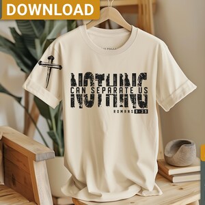 以下が含まれることがあります： ベージュのTシャツに、黒いグラフィックプリントが施されています。プリントには「何も私たちを分離することはできない 何も ローマ人への手紙 8:39」と書いてあります。グラフィックは使い古されたような風合いになっており、左上の角には釘のデザインが施されています。