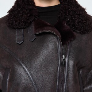 Detail shot of heavy-duty metal buckles, leather straps, and soft sheepskin wool on a bespoke B3 winter jacket for women.