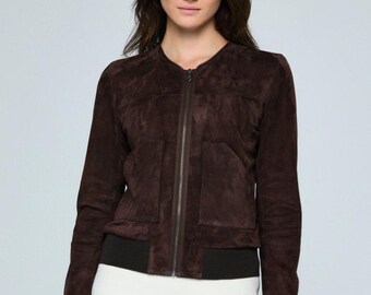 May include: A dark brown suede bomber jacket with a zip-up front, two front pockets, and black ribbed cuffs and hem. The jacket is worn over a white top and beige pants.