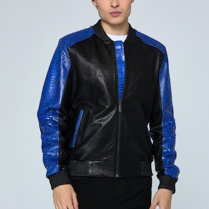 May include: Black leather bomber jacket with blue snakeskin-textured sleeves and accents. The jacket has a zip-up front and ribbed cuffs and hem. The model is wearing black pants and a white undershirt.