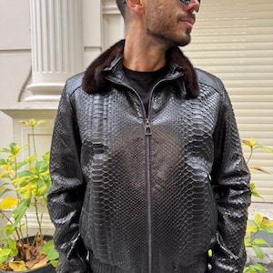 May include: A black leather jacket with a snakeskin pattern and a fur collar. The jacket has a zipper closure and a ribbed knit waistband.