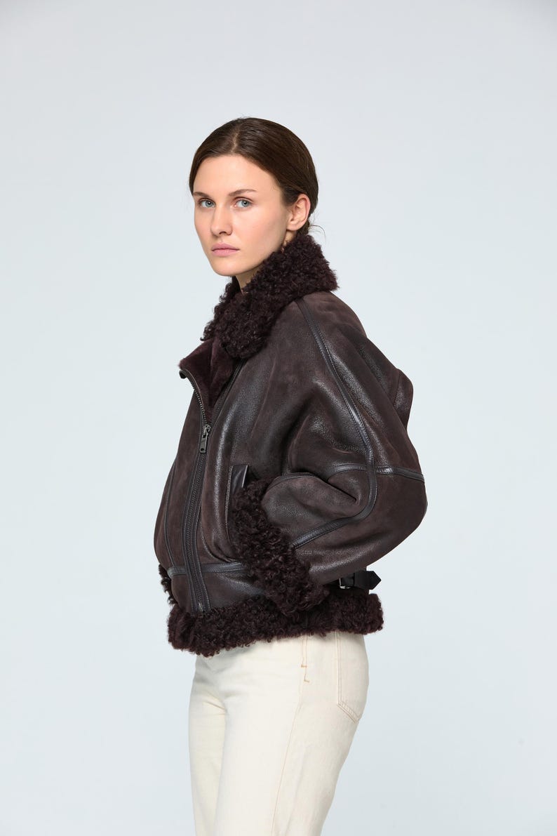 Close-up texture of genuine brown sheepskin leather and premium natural shearling fur lining on a luxury winter bomber jacket.