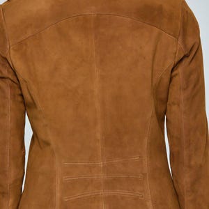 May include: A brown suede jacket with a tailored fit. The jacket features a stand-up collar, long sleeves, and a series of horizontal stitched details near the waist. The back view showcases the jacket's design and construction.