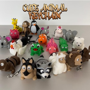 May include: A collection of 18 colourful animal keychains. The keychains are made of soft, squishy plastic and feature a variety of animals, including a giraffe, penguin, monkey, unicorn, elephant, koala, chicken, frog, lizard, polar bear, dachshund, husky, raccoon, and llama. The keychains are all attached to metal rings and chains.