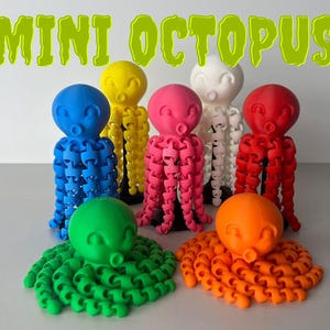 Könnte beinhalten: Sieben Miniatur-Oktopus-Figuren in verschiedenen Farben: Blau, Gelb, Rosa, Weiß, Rot, Grün und Orange. Jeder Oktopus hat ein süßes Gesicht und acht Tentakel.