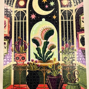 May include: A completed jigsaw puzzle depicting a dark room with arched windows, a crescent moon, and stars. Various carnivorous plants in decorative pots, including a Venus flytrap under a glass dome and skull-shaped planters, are displayed.