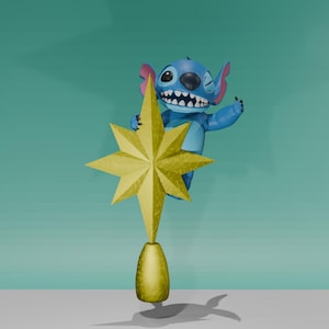 May include: A blue cartoon character with one eye closed is holding onto a gold star-shaped Christmas tree topper. The topper is attached to a gold base.