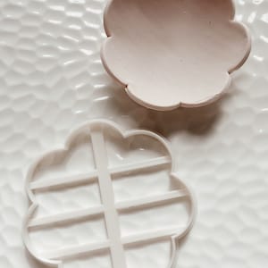 Peut inclure: Deux moules en silicone blanc en forme de fleur. Le plus grand moule a une surface lisse et le plus petit moule a une grille.