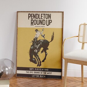 May include: Framed vintage poster for the Pendleton Round-Up rodeo event. The poster features a cowboy riding a bucking bronco, set against a yellow and black background. Text includes "Pendleton Round Up" and event details from 1940.