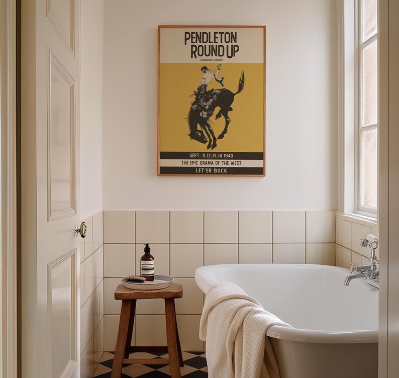 May include: A bathroom scene featuring a framed "Pendleton Round Up" poster with a rodeo theme. The poster is above a white bathtub. A small wooden stool holds a bottle and brush. The room has white tile and a black and white checkered floor.
