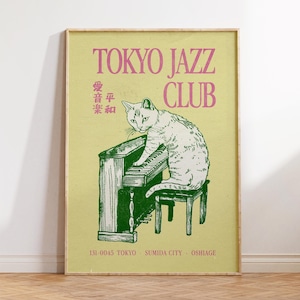 May include: A framed poster with a vintage aesthetic. The poster features a green and white illustration of a cat playing a piano, with the text "TOKYO JAZZ CLUB" in pink. Additional Japanese text and location details are also included.
