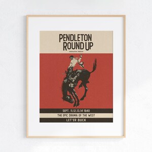 May include: Framed vintage poster for the Pendleton Round Up rodeo event. The poster features a cowboy riding a bucking bronco, with text including "Pendleton Round Up" and "Sept. 11,12,13,14 1940". The colour scheme is red, beige, and black.