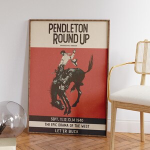 May include: Framed vintage poster for the Pendleton Round-Up rodeo event. The poster features a cowboy riding a bucking bronco against a red background. Text includes "Pendleton Round Up" and event details.