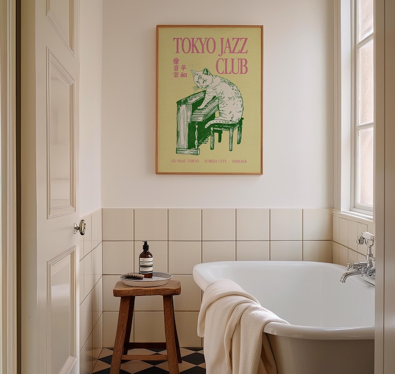 May include: A framed poster with the text "TOKYO JAZZ CLUB" in pink lettering. The poster features a green illustration of a cat playing a piano. The poster is hanging above a white bathtub in a bathroom setting.