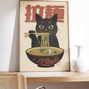 May include: A vintage-style poster featuring a black cat eating ramen noodles with chopsticks. The poster has a red background with Japanese characters that say "Ramen Cat".
