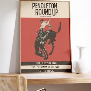 May include: A framed vintage poster advertising the Pendleton Round Up rodeo. The poster shows a cowboy on a bucking bronco against a red backdrop. Text includes "Pendleton Round Up," "Pendleton, Oregon," and event details from 1940.