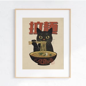 May include: A black cat with green eyes is eating ramen noodles from a bowl with chopsticks. The bowl is red and white with a dragon design. The text "拉麺" is written in red on a white background.