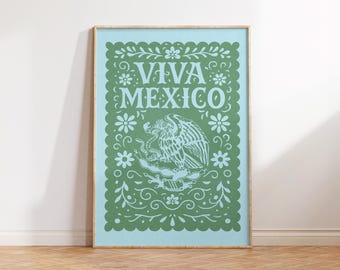 May include: A framed art print with a light blue background and a green design. The design features the words "VIVA MEXICO" in stylized lettering, along with an eagle emblem and floral accents. The print is displayed on a wooden floor.